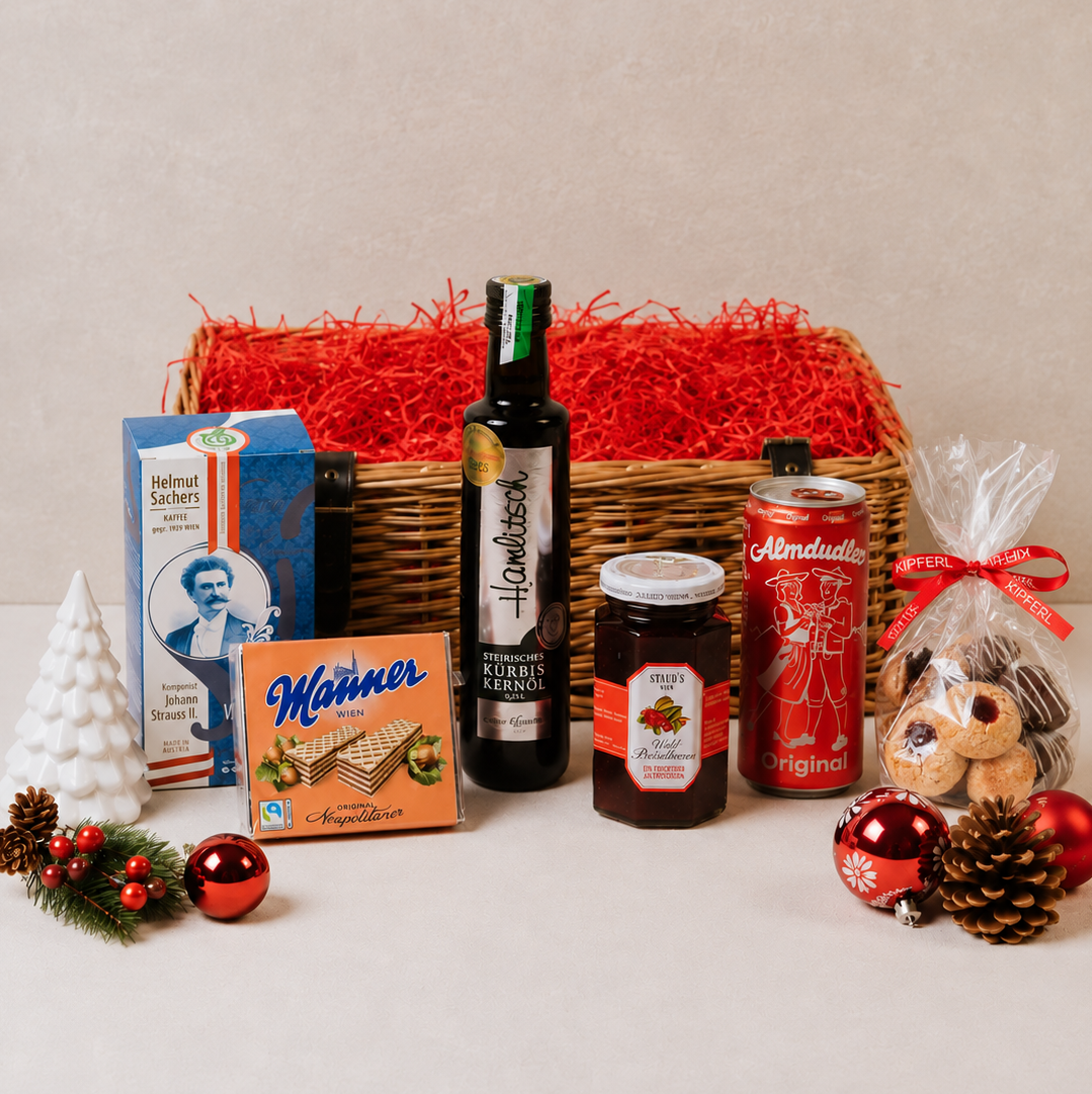Small Austrian Christmas gift hamper in a wicker basket with Kipferl Christmas cookies, Styrian pumpkin seed oil, Austrian coffee, Staud's jam, Almdudler and Manner wafers
