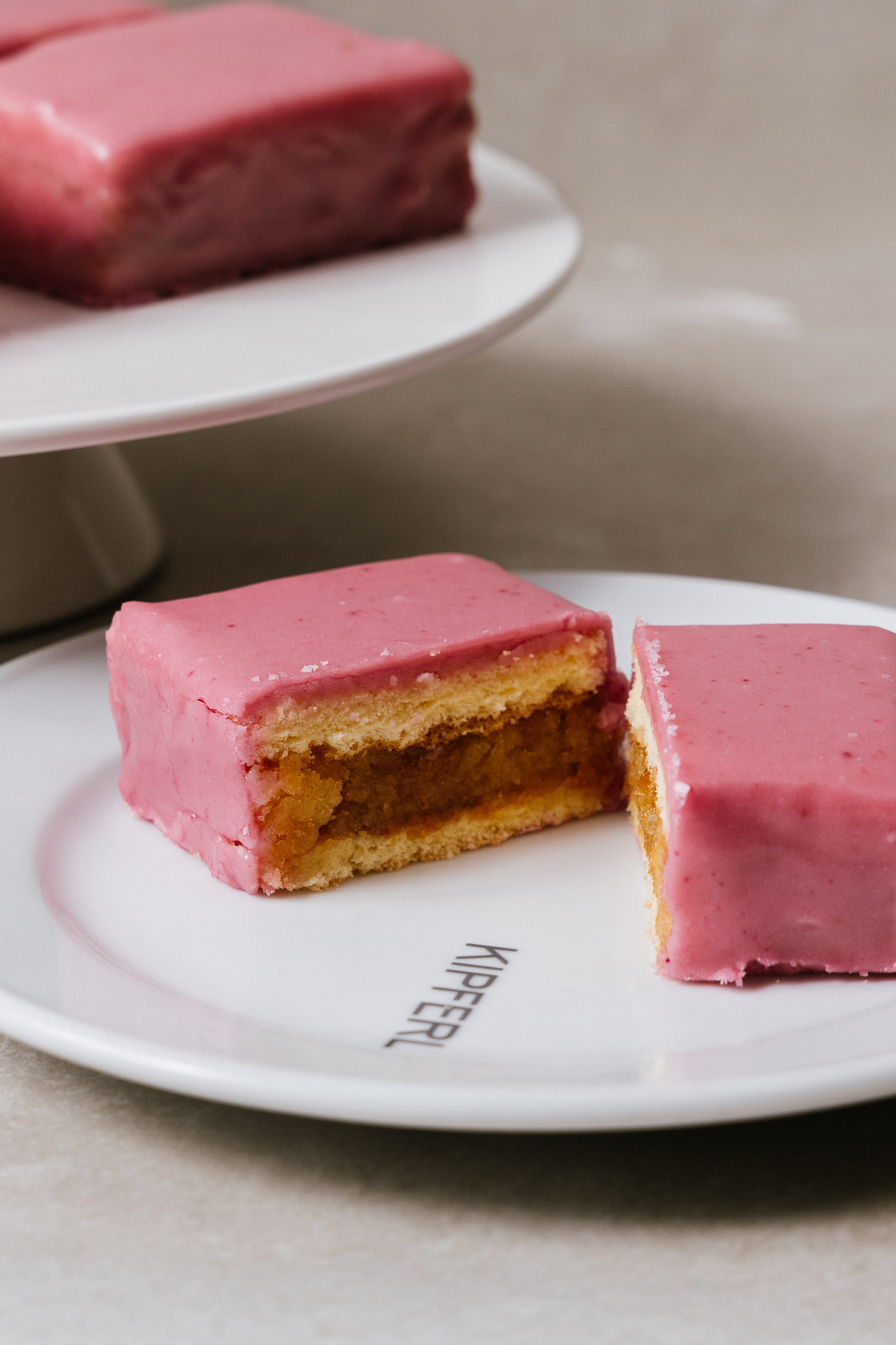 Side view of Punschkrapferl showing pink icing and sponge layers